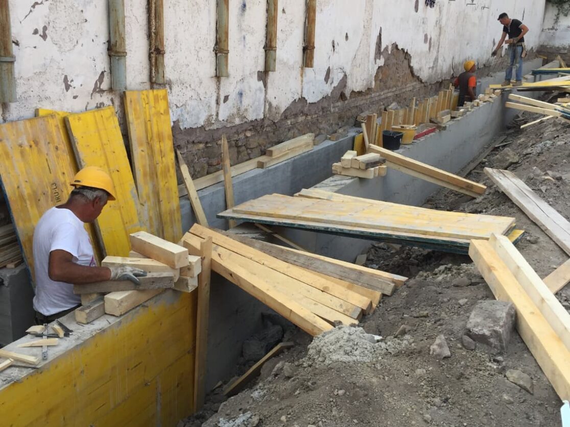 Un uomo lavora su una parete con una scala durante la realizzazione del nuovo Rettorato dell'Università Roma Tre, con fondamenta solide e stabili garantite dalla E&G.